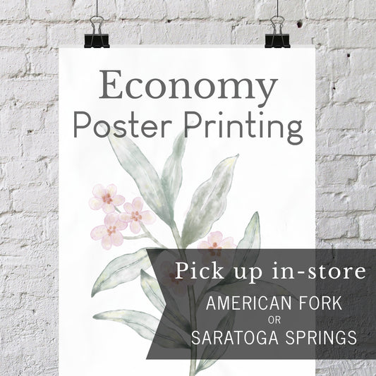 A vertical poster print with the text 'Economy Poster Printing' and a watercolor-style botanical illustration hangs against a white brick wall with two black binder clips. A dark translucent banner at the bottom reads 'Pick up in-store AMERICAN FORK OR SARATOGA SPRINGS'.