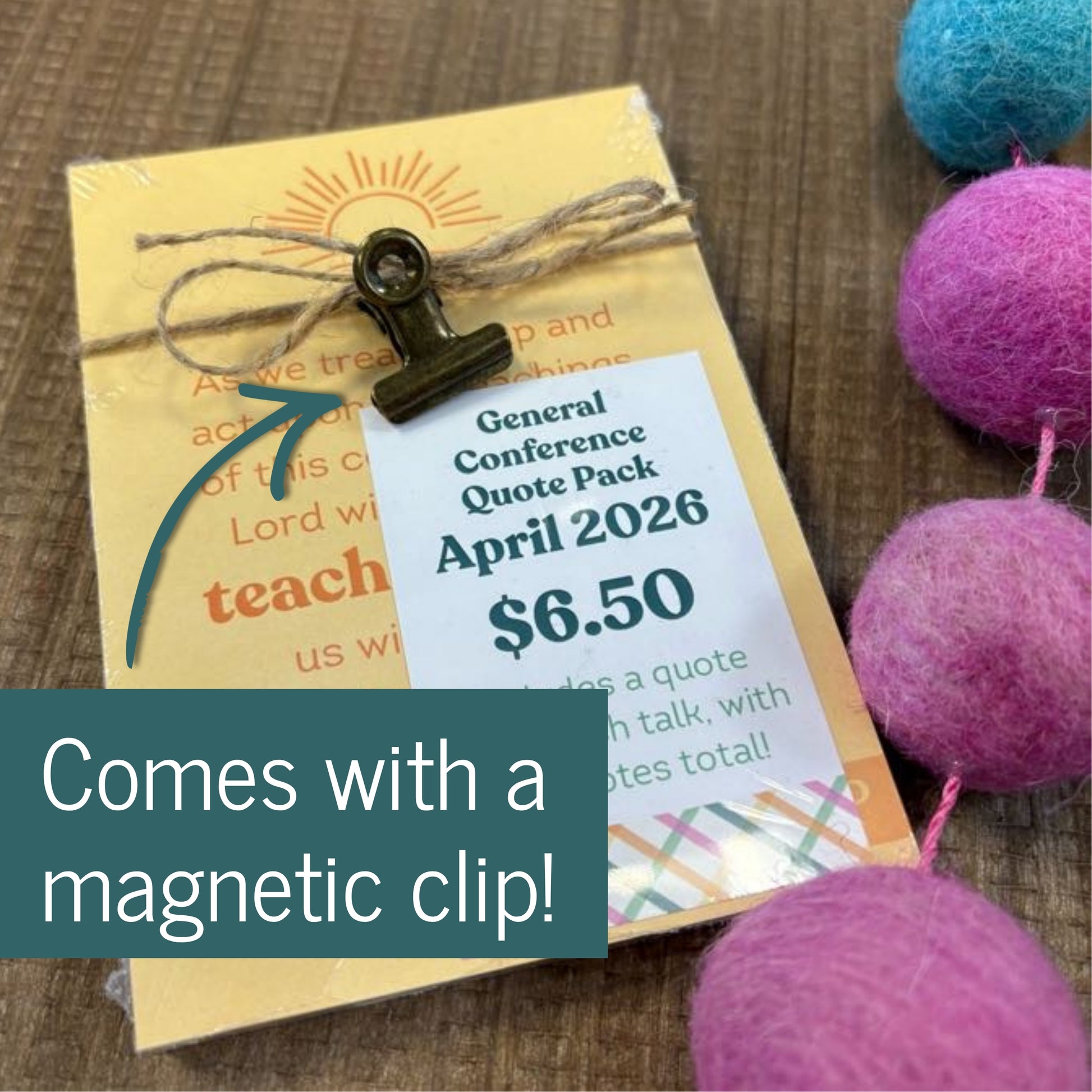 General Conference Quote Pack with a magnetic clip on a wooden surface with colorful balls.